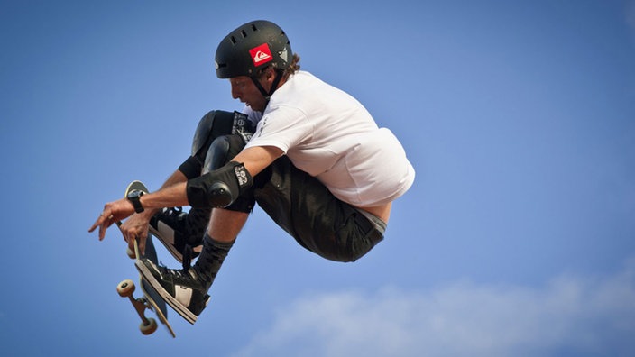 Skater Tony Hawk hebt mit seinem Skateboard ab. | Bildquelle: Mauritius Skater Tony Hawk hebt mit seinem Skateboard ab.
