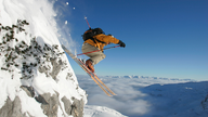 Ein Skifahrer springt über einen Vorsprung im Berg.
