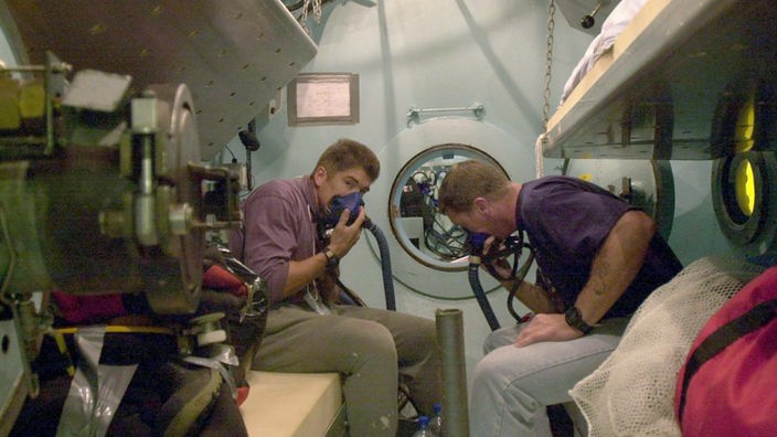 Taucher überprüfen ihre Ausrüstung in einer Druckkammer.