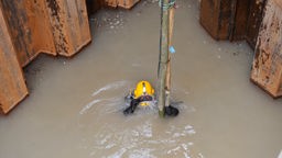 Ein Industrietaucher taucht in der Baustelle eines Abwasserkanals in Köln.