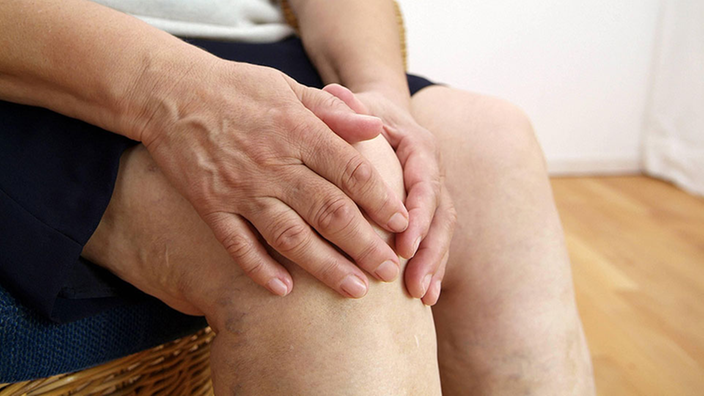 Eine Frau hält sich ihr schmerzendes Knie.