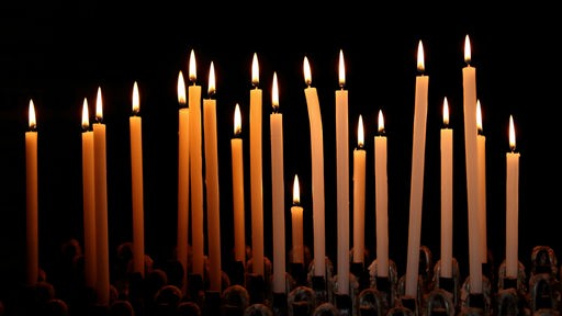 Brennende Kerzen vor schwarzem Hintergrund