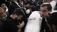 Eine jüdische Gemeinde trägt einen in ein Tuch gewickelten Leichnam zum Grab