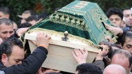 Männer tragen einen verzierten Holzsarg bei einem muslimischen Trauerzug