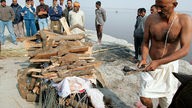 Männer am Ganges bereiten eine hinduistischeFeuerbestattung vor