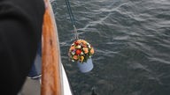 Eine geschmückte Urne wird in die Ostsee hinabgelassen