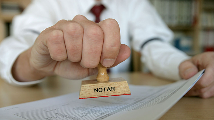 Hand hält einem Stempel mit Ausschrift "Notar"