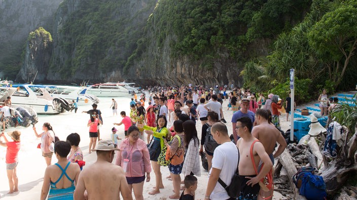 Eine große Anzahl von Touristen an einem weißen Sandstrand.