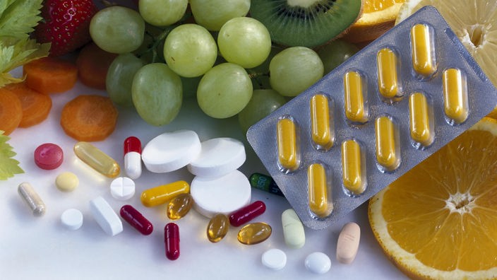 Früchte und Tabletten mit Vitaminen und Mineralien