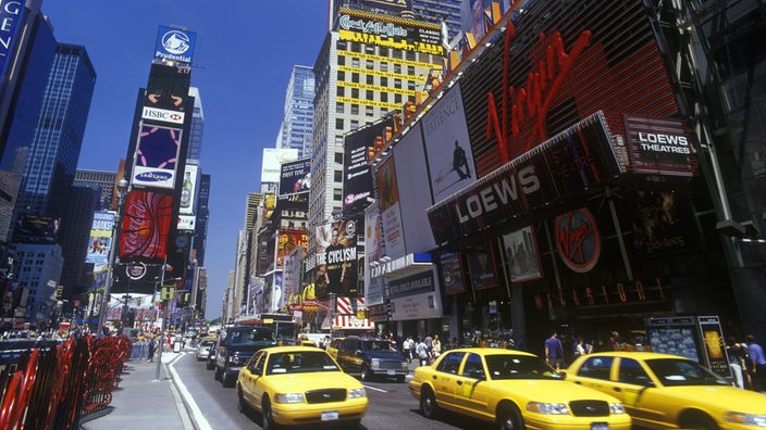 Die Aufnahme zeigt den Times Square heute - mit Lichterreklamen, gelben Taxis und Spaziergängern