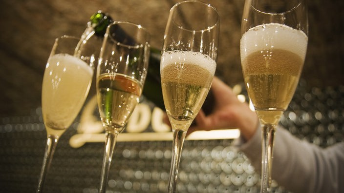 Vier halbvolle Champagnergläser werden gefüllt