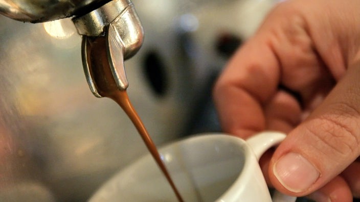 Espresso fließt aus einem Kaffeevollautomaten in eine weiße Espressotasse.