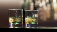 Zwei gefüllte Whiskygläser stehen auf einem Tresen