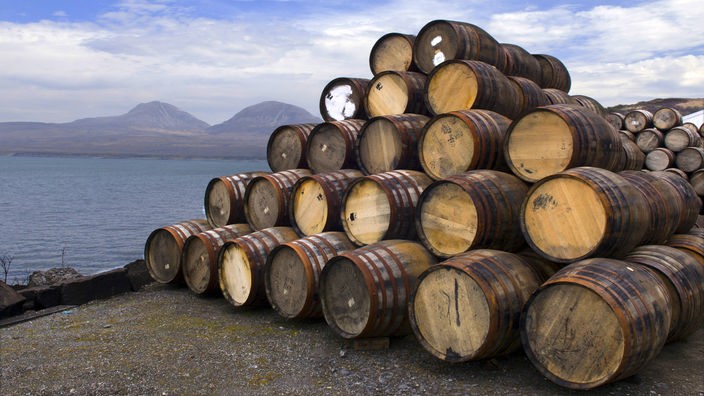 Whiskyfässer vor Landshcaft in Schottland