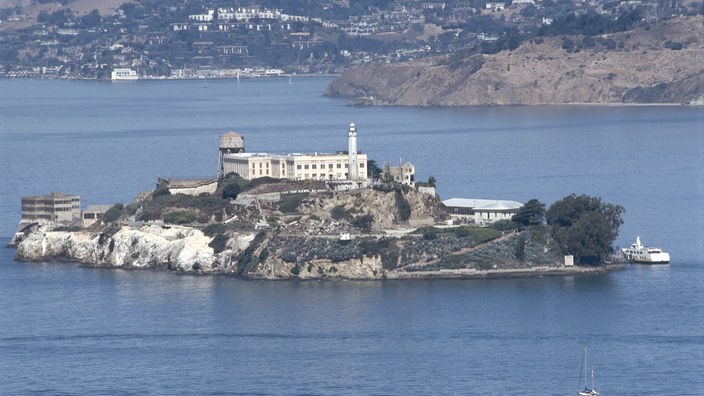 Hochsicherheitsgefängnis von Alcatraz auf einer Felseninsel, dahinter die Stadt San Francisco