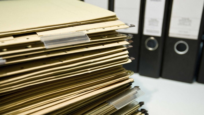 Unzählige Hängeregister liegen gestapelt auf einem Schreibtisch mit Aktenordnern | Bildquelle: picture alliance / imageBROKER Unzählige Hängeregister liegen gestapelt auf einem Schreibtisch mit Aktenordnern