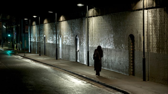 Frau läuft bei Nacht durch eine Straße.