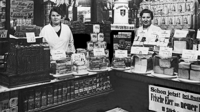 Schwarzweiß-Aufnahme von zwei Verkäuferinnen in einem Laden