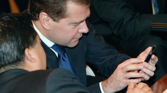 Russlands Ministerpräsident Dmitri Medwedew schaut auf ein Handy.
