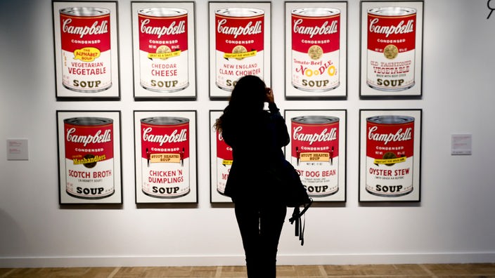 Eine Museumsbesucherin vor Andy Warhols "Campbells Soup Cans"