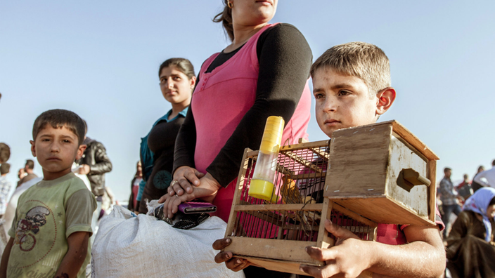 Ein kurdischer Junge hält den Käfig seines Kanarienvogels fest in der Hand.