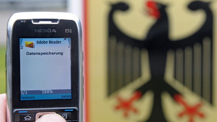 Handy-Display mit Aufschrift "Datenspeicherung" vor Schild mit Bundesadler.