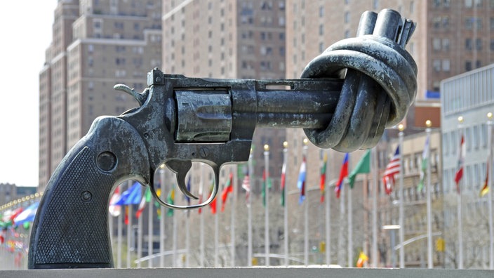 Skulptur eines Revolvers, dessen Lauf verknotet ist, vor dem UN-Hauptquartier in New York. | Bildquelle: imago stock&people Skulptur eines Revolvers, dessen Lauf verknotet ist, vor dem UN-Hauptquartier in New York.