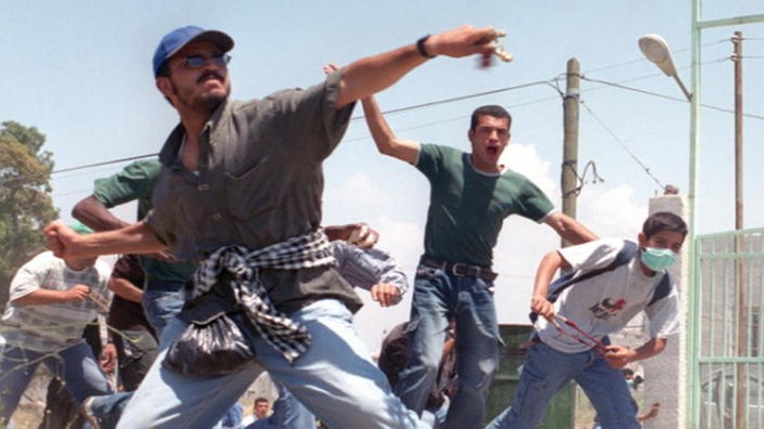 Palästinensische Jugendliche werfen Steine in Richtung israelischer Soldaten.