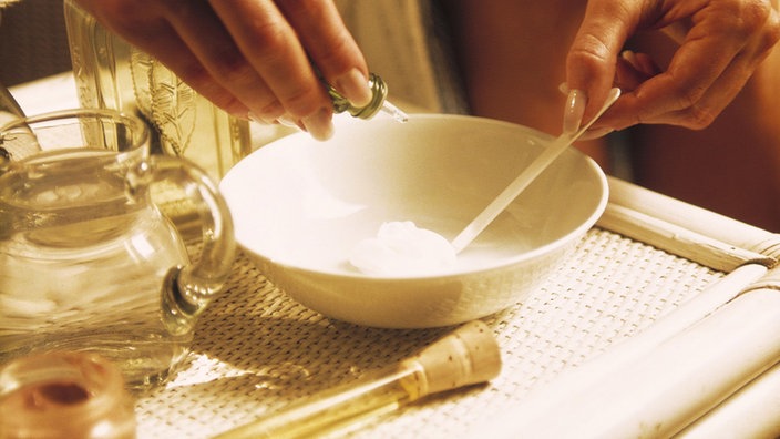 Eine Frau bereitet in einer Schüssel Öle für eine Aromatherapie zu | Bildquelle: Mauritius/Schlief Eine Frau bereitet in einer Schüssel Öle für eine Aromatherapie zu