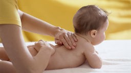 Ein Baby wird am Rücken massiert
