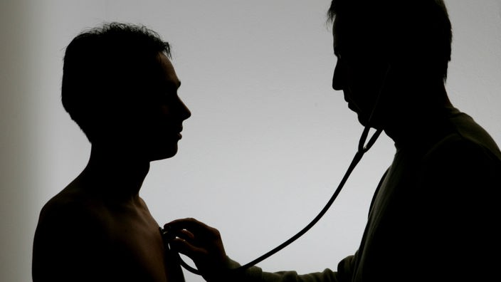 Ein Mann untersucht einen Patienten mit einem Stethoskop.