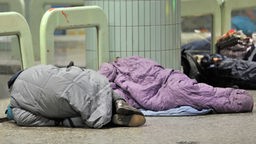 In Schlafsäcke gehüllt oder nur mit einer Jacke bedeckt schlafen Obdachlose im Bahnhof Frankfurt Hauptwache.