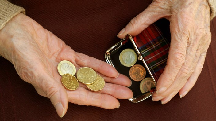 In der Hand einer Rentnerin liegt Kleingeld.