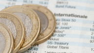 Münzen auf Zeitung mit Schriftzug Zinsen