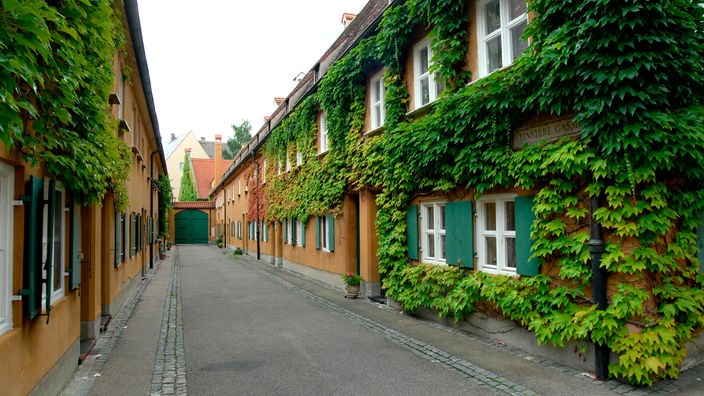 In der Augsburger Fuggerei stehen mit wildem Wein bewachsene Häuser.