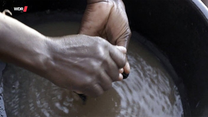 Frauenhände in einer Schüssel mit Wasser und Quecksilberlösung