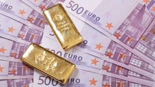 Zwei kleine Goldbarren liegen auf 500-Euro-Scheinen
