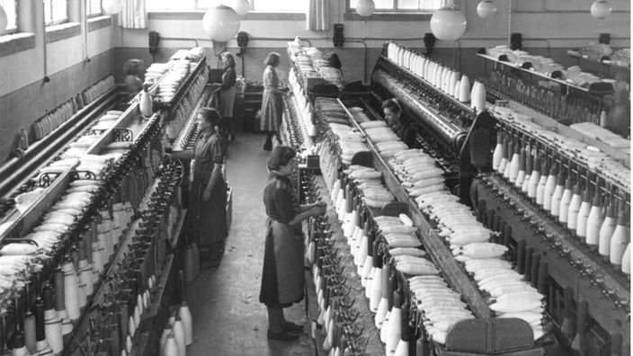Schwarz-weiß-Aufnahme mit Frauen in einer Textilindustrie.