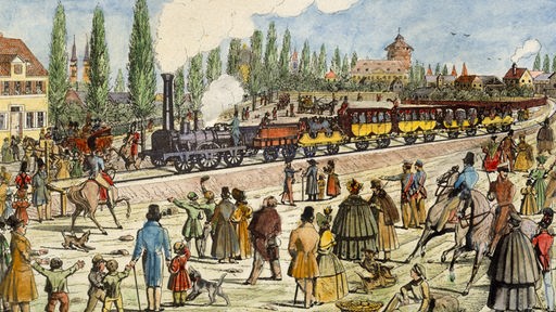 Eine Dampflokomotive zieht mehrere zum Teil überdachte Personenwagen durch eine Landschaft; im Vordergrund viele Schaulustige.