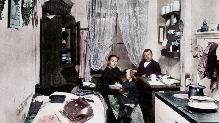 1905: Kolorierte Fotografie einer Familie in ihrer kleinen Küche