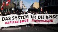 Demonstranten tragen ein Transparent mit der Aufschrift "Das System ist die Krise – Kapitalismus zerschlagen"
