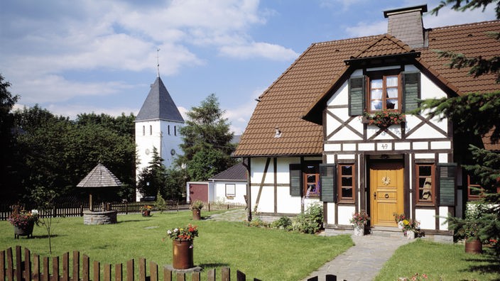 Ein Fachwerkhaus mit einem großen Vorgarten und einem Holzzaun um das Grundstück.