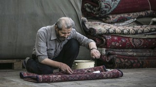 Ein Mann arbeitet an einem Teppich auf einem Teppichbasar in Teheran
