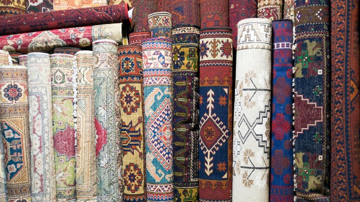 Viele bunte aufgerollte türkische Teppiche nebeneinander