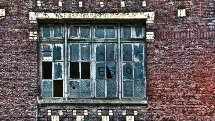 Verlassenes Gebäude mit zerbrochenen Fensterscheiben und Graffiti