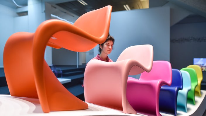 Mehrere verschiedenfarbige Plastikstühle in einer Ausstellung