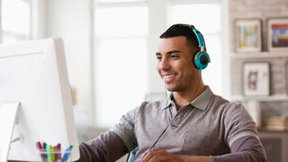Ein Mann im Büro am Computer mit Kopfhörern