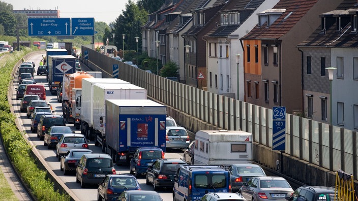 Stark befahrene A40. Direkt daneben Mietshäuser mit kleiner Schallschutzwand | Bildquelle: Mauritius Stark befahrene A40. Direkt daneben Mietshäuser mit kleiner Schallschutzwand