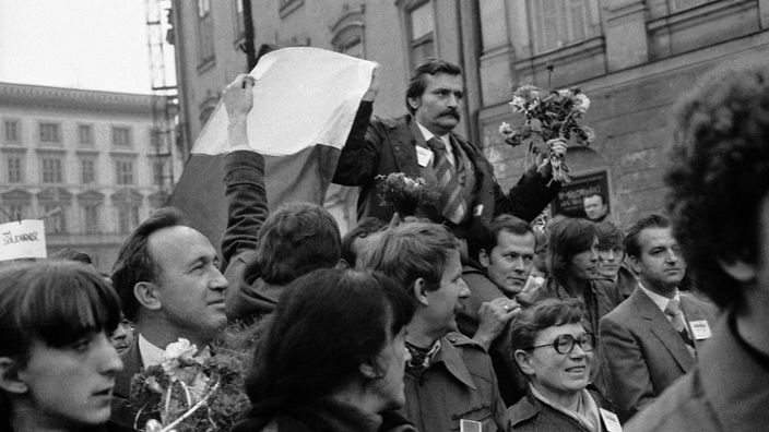Schwarzweiß-Foto: Lech Wałęsa wird von einer jubelnden Menge getragen