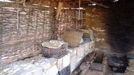 Ein Pfostenbau mit Pultdach mit einer alten Herdstelle der Steinmetze und eine erste Trockenmauer.